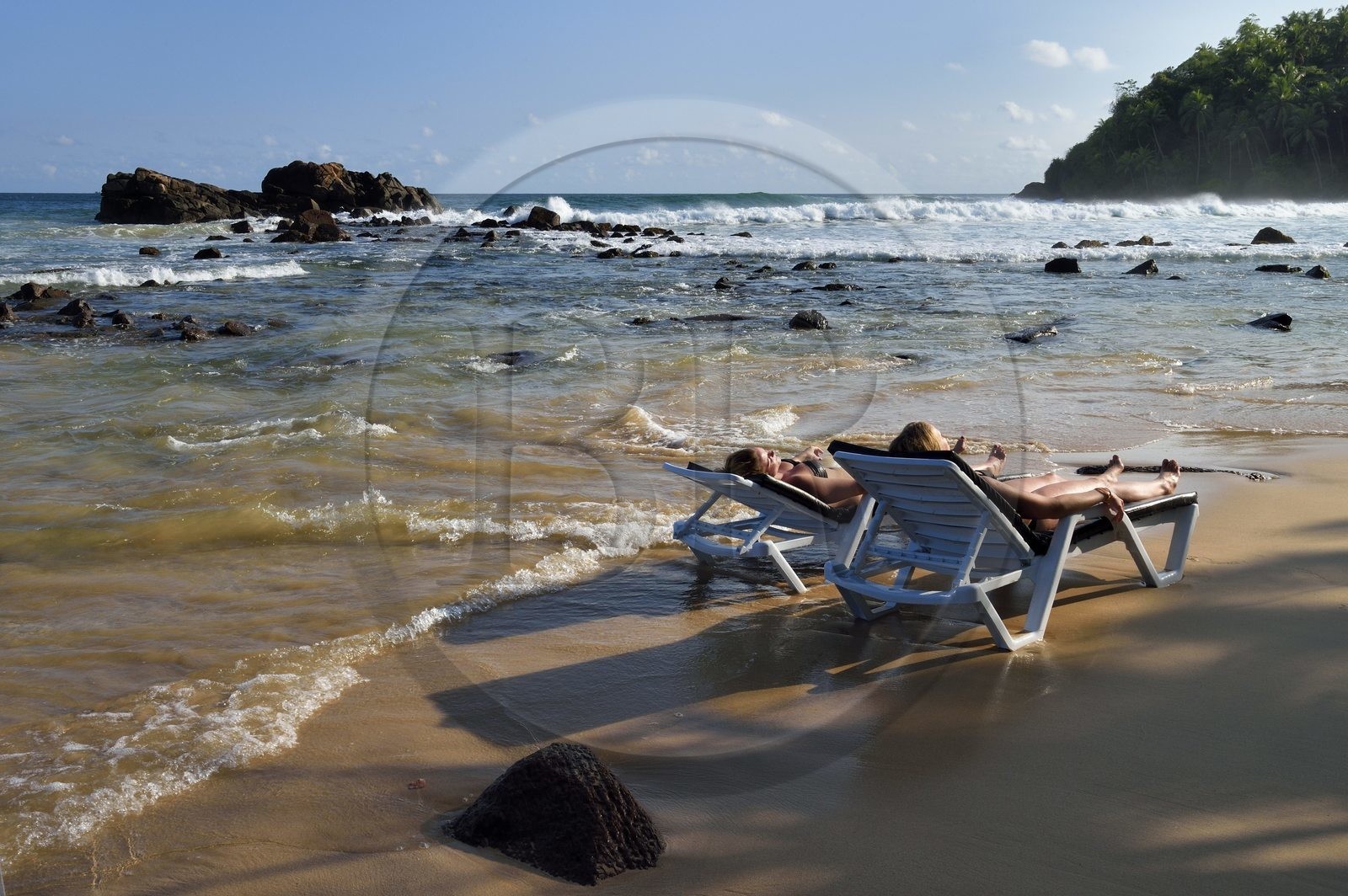 Sri Lanka, Province du Sud, Matara (district), Weligama, plage de Mirissa, femmes bronzant sur une chaise longue les pieds dans l'eau