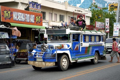 Philippines, province de Nueva Ecija, Bambang, jeepney (jeep allongée pour le transport de passagers) avec passagers sur le toit dans la rue principale