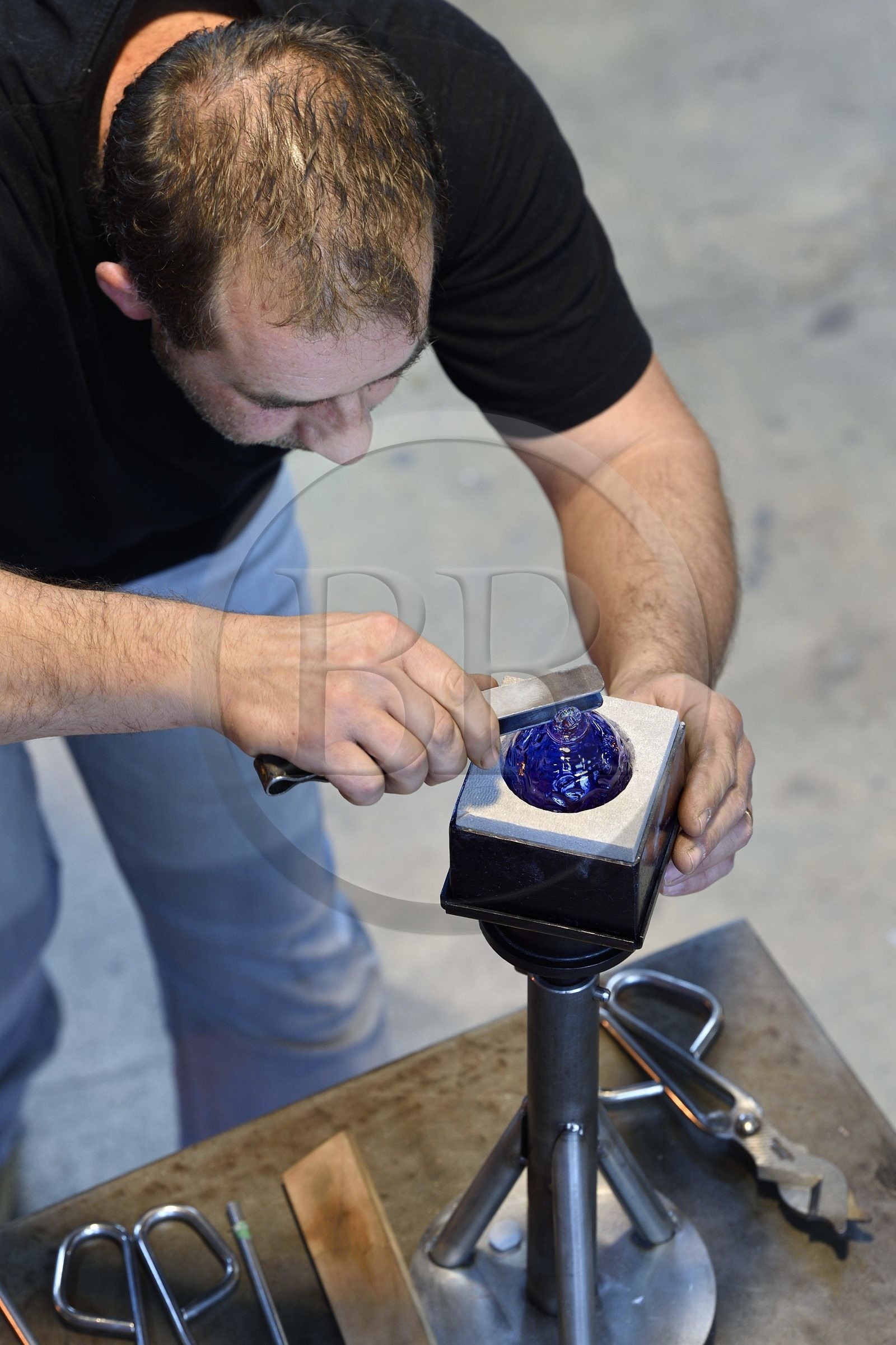 France, Moselle (57), Meisenthal, Centre international d’Art verrier (CIAV), l'atelier de soufflage, fabrication artisanale d'une boule de Noël, finalisation de la mise en place du crochet en verre