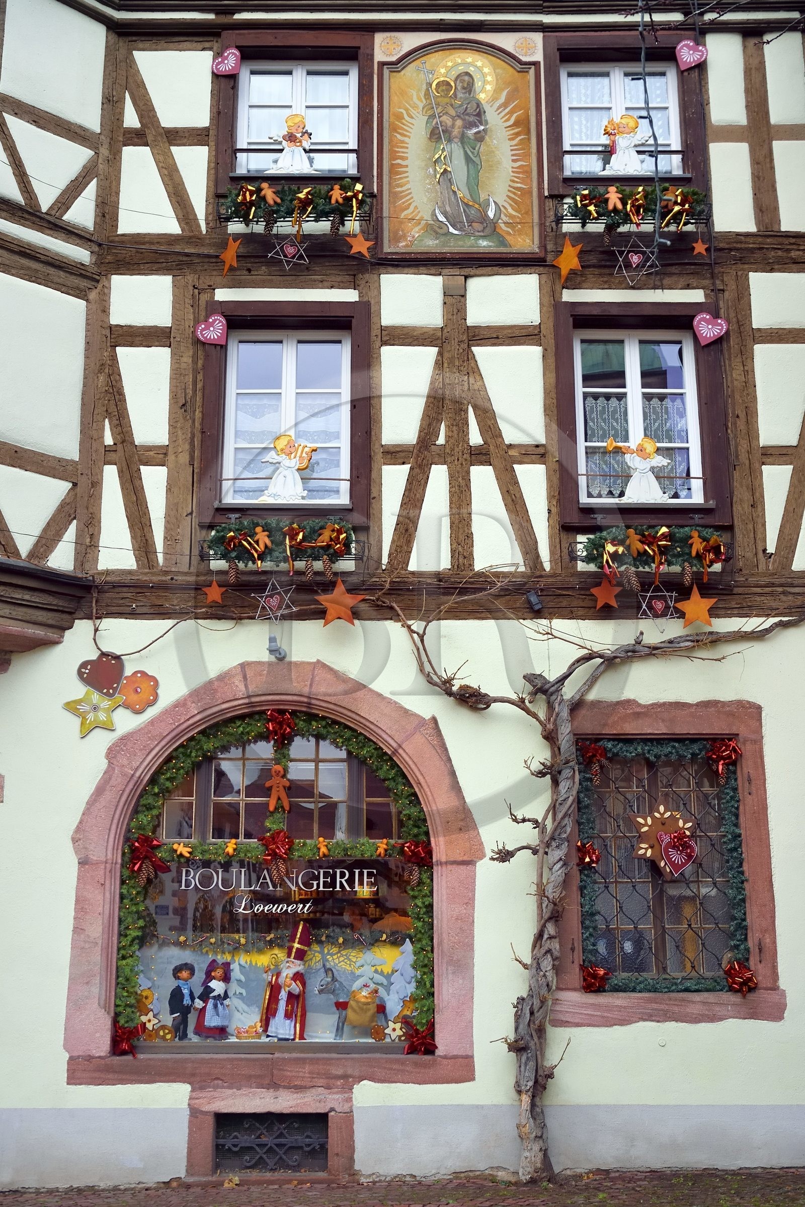 France, Haut-Rhin (68), Kaysersberg, maison à pans de bois de la boulangerie Loewert avec un tableau de la Vierge à l'Enfant sur la facade et des décorations de Noël