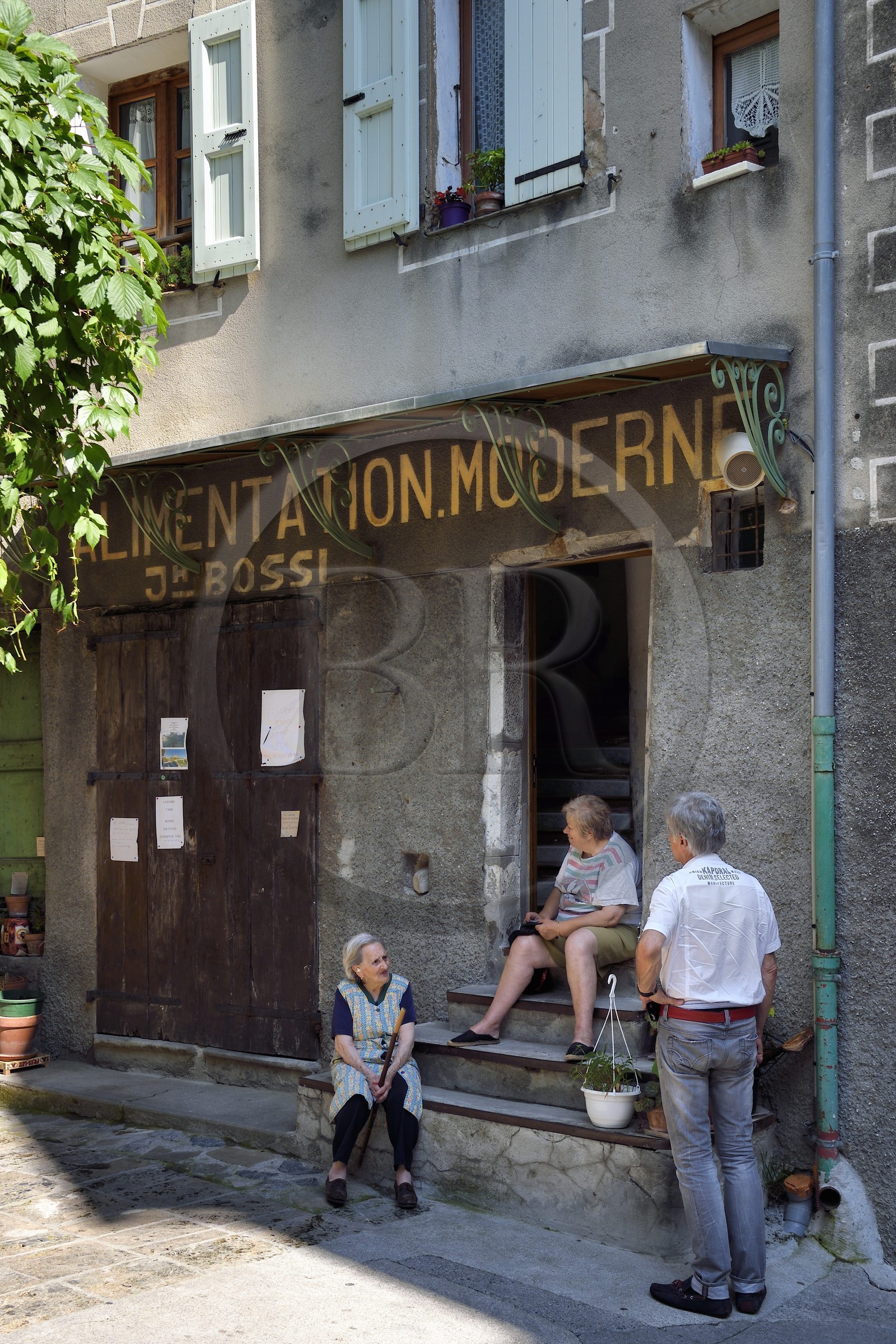 France, Alpes de Haute Provence, Entrevaux Medieval city fortified by Vauban, discussion in front of the old town grocery store in la Porte Royale street