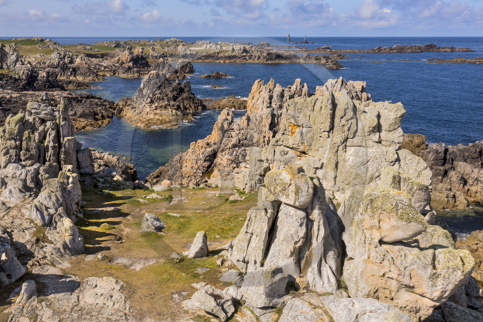 France, Finistère (29), Mer d'Iroise, Ile d'Ouessant, rochers façonnés par les tempêtes au pied du phare du Créac’h, le phare de Nividic sur la Pointe de Pern en arrière plan (vue aérienne)