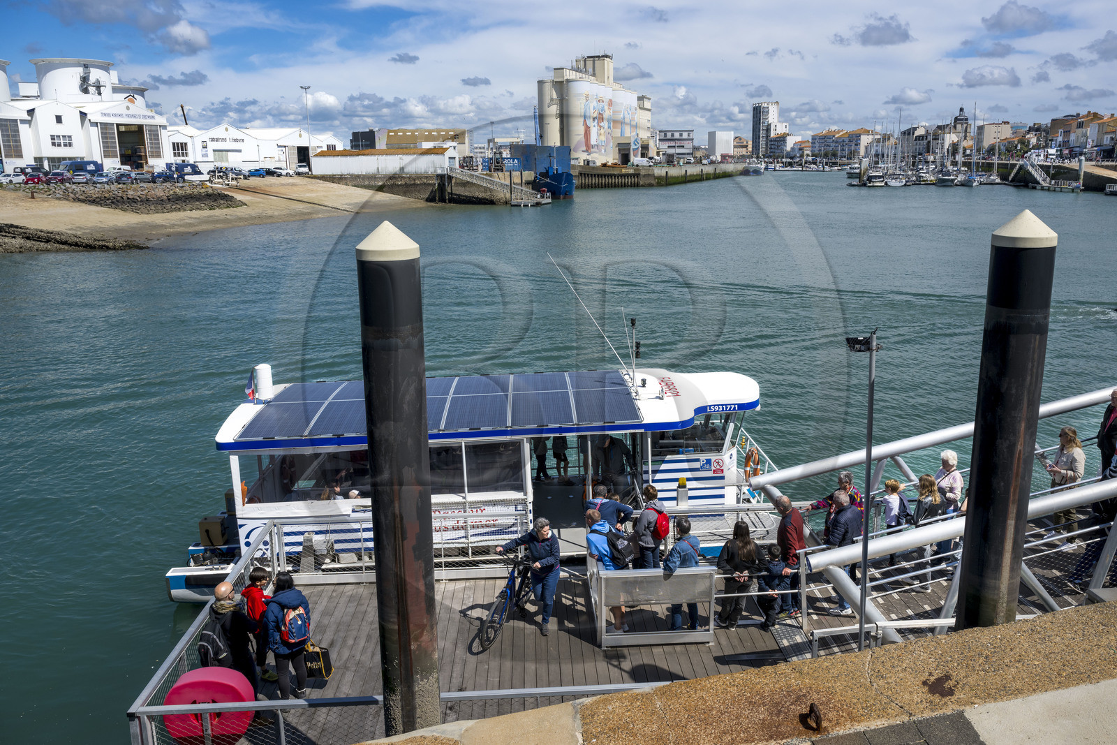 France, Vendée (85), Les-Sables-d'Olonne, cyclistes utilisant le bac traversant le port, fresque retracant l'histoire de la ville peinte sur les silos de la coopérative Cavac par l'artiste basque Taroe en arrière plan