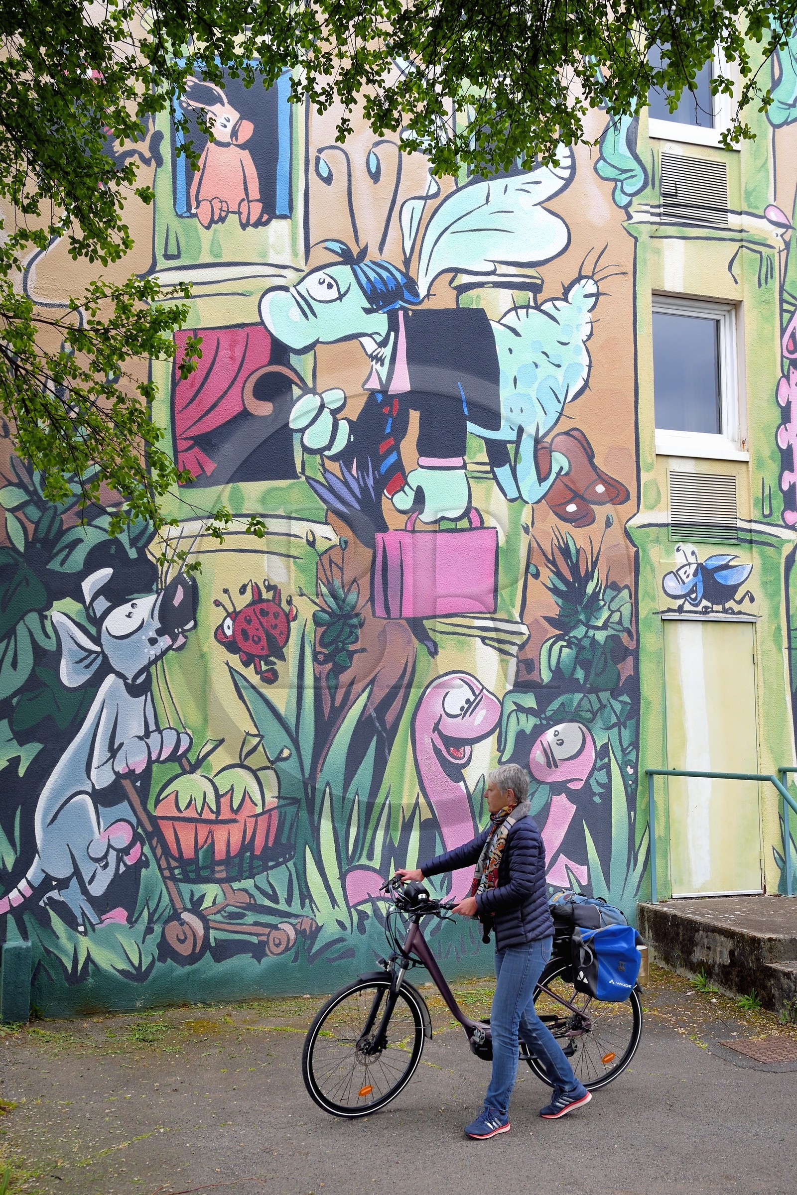 France, Charente (16), Angoulême, Rue Pierre Sémard , cycliste faisant la véloroute La Flow Vélo devant Le Jardin Extraordinaire, mur peint d'après un dessin original de Florence Cestac et réalisé par la Cité de la création en 2001