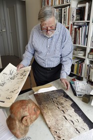 France, Paris, the french paleontologist and paleoanthropologist Yves Coppens, professor at the College de France, in the office of his home in Paris, he shows us a picture of Laetoli footprints under the watch of the supposed reproduction of Lucy's face