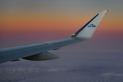 Norvège, aile d'un avion KLM en vol au dessus des nuages au coucher de soleil