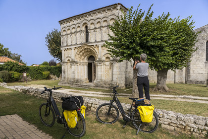 France, Charente Maritime, Echillais, cyclists traveling along the cycle route in front of the 12th century Romanesque church of Notre-Dame, classified as a historic monument